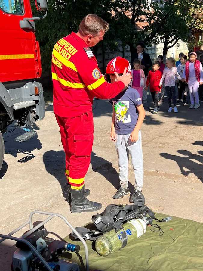 Copil care probează echipamentul pompierilor